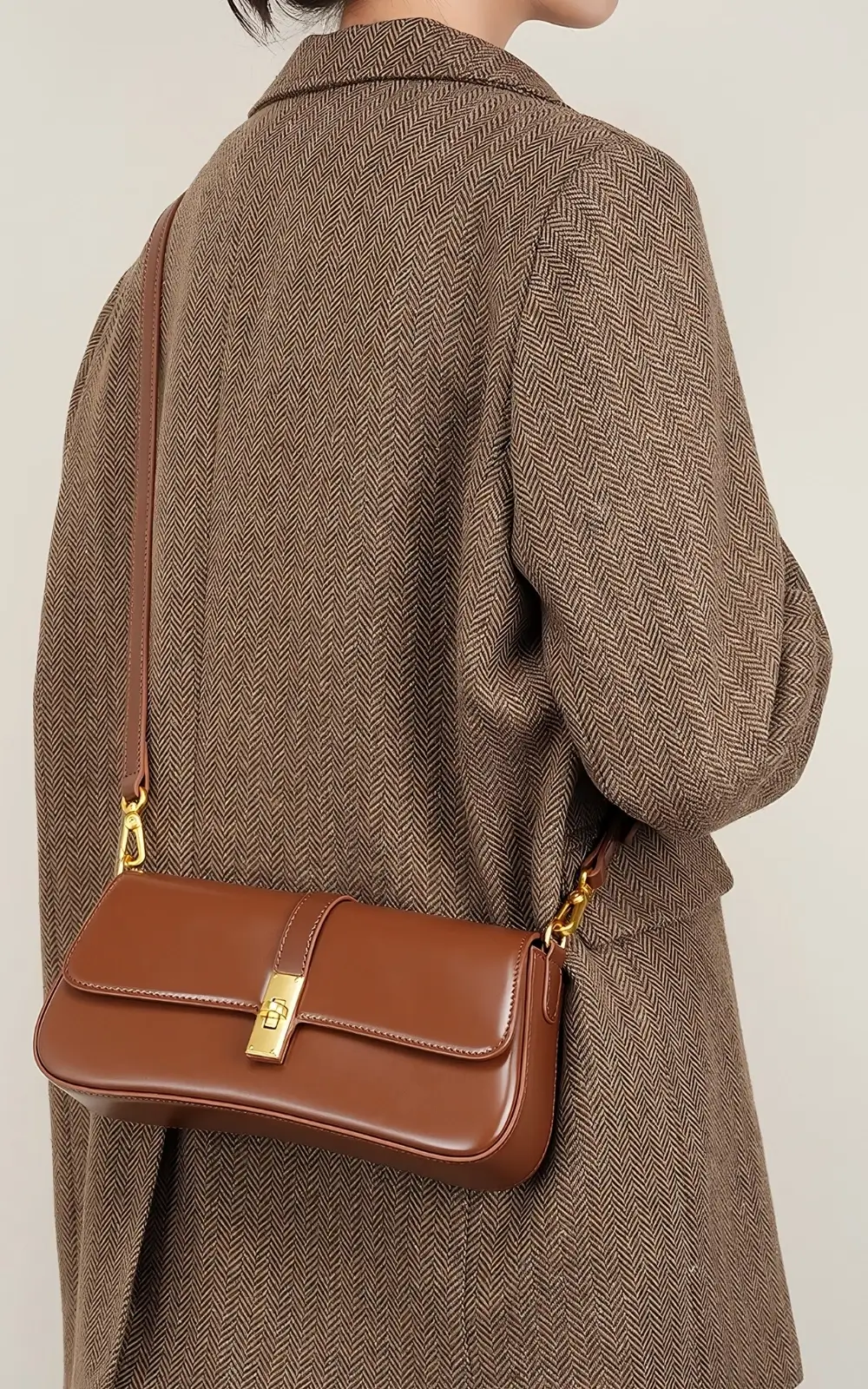 Lifestyle shot: brown Marisse Baguette Bag draped over the shoulder on a marble surface