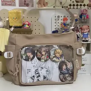 A khaki Ita messenger bag with a transparent front window displaying anime pins and manga art, styled in a Japanese Harajuku aesthetic
