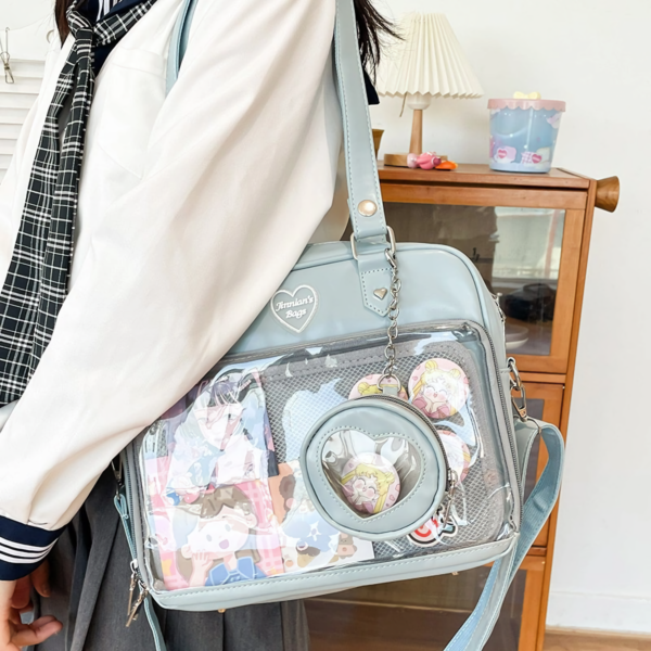 dusty blue ita bag modeled over shoulder with colorful pins inside the window