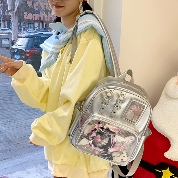 Person wearing clear window ita backpack outdoors with colorful pin display