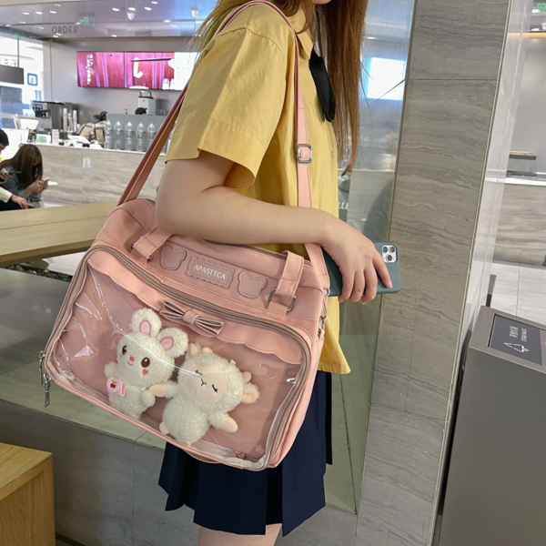 Black nylon ita bag hanging on rack with white bunny plush inside