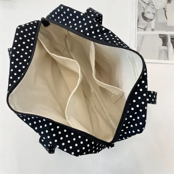 Open black polka dot ita bag showing interior dividers and zippered pocket
