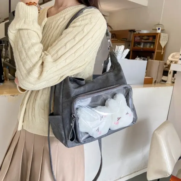 Slouchy crossbody ita bag with clear vinyl window displaying two white plush toys
