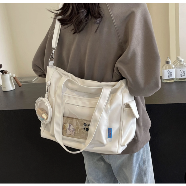 Person holding white ita bag with visible plush keychain inside window