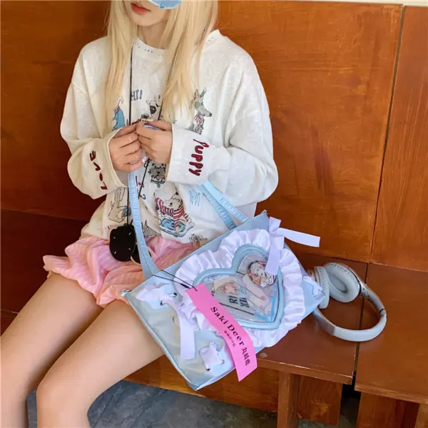 Pink ruffle trim heart ita bag held by person showing clear window and adjustable strap
