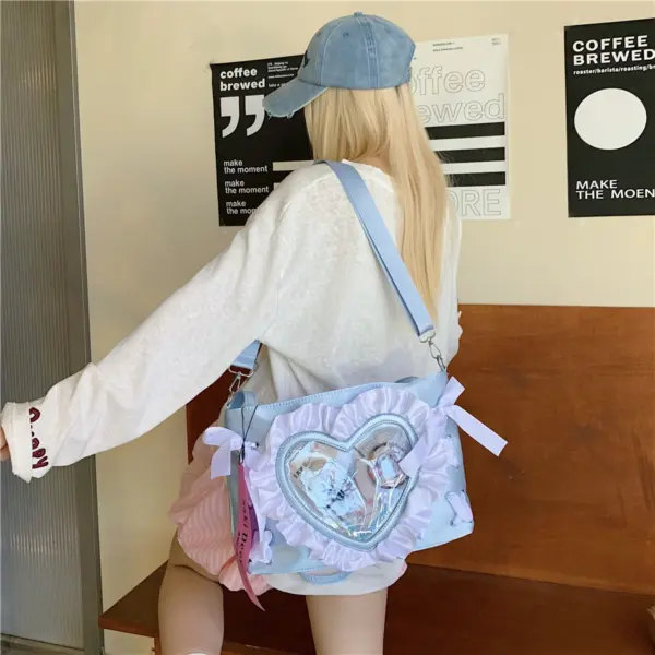 Light blue heart ita bag worn crossbody showing clear PVC window and ruffle trim