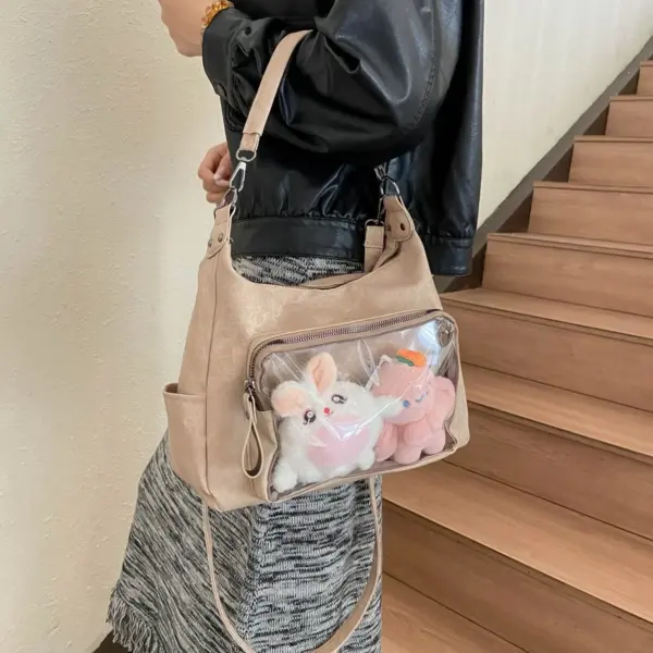 Close up of clear vinyl window on light brown ita bag with plush toys inside