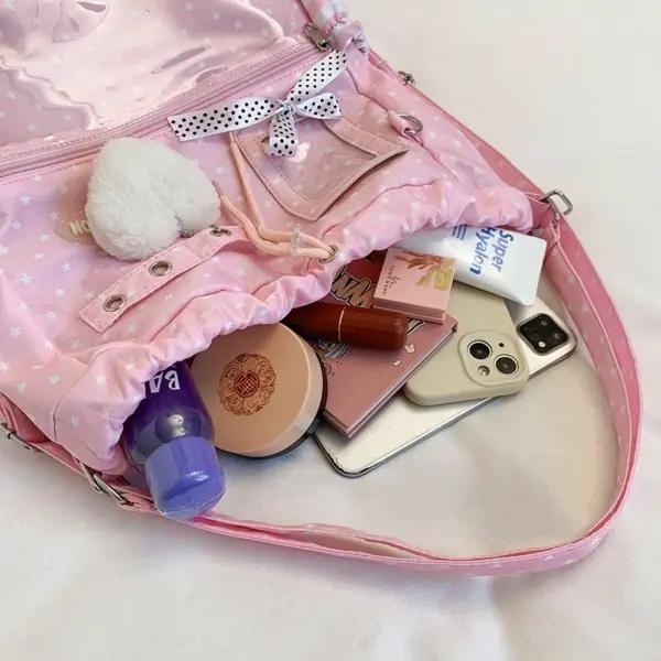 Open pink star pattern ita bag interior filled with smartphone, mirror, and makeup products