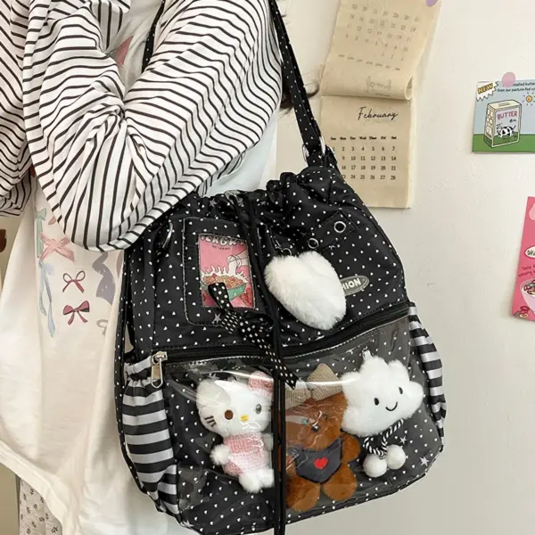 Person wearing white polka dot drawstring ita bag with clear window showing two plush toys