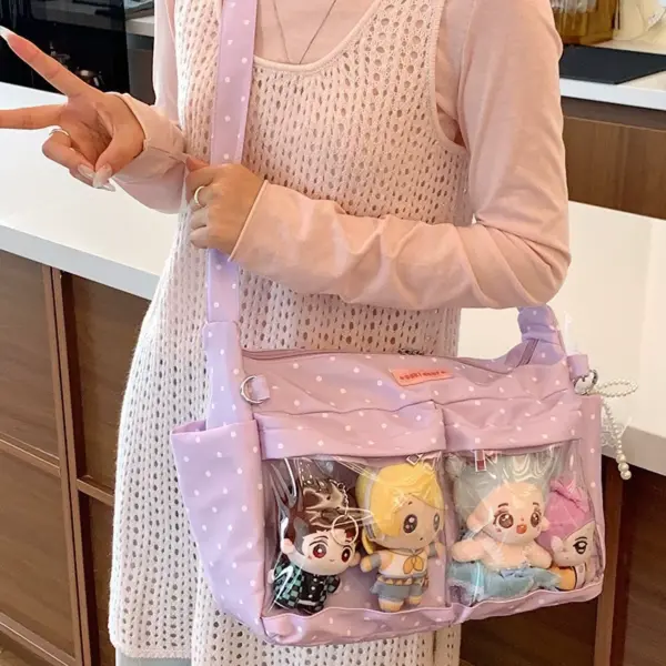 Person wearing light blue polka dot ita bag with plush dolls visible in clear window
