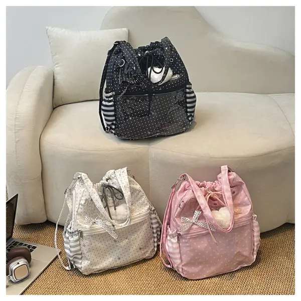 Three drawstring ita bags in black, white, and pink polka dot arranged on a white sofa
