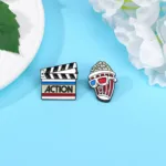 Close up of Clapperboard and Popcorn Enamel Pins