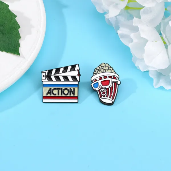 Close up of Clapperboard and Popcorn Enamel Pins
