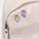 Heart enamel pins on backpack.webp