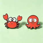 Crab and Octopus Enamel Pins on Green Background